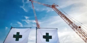 クレーンのある建設現場と緑十字の旗